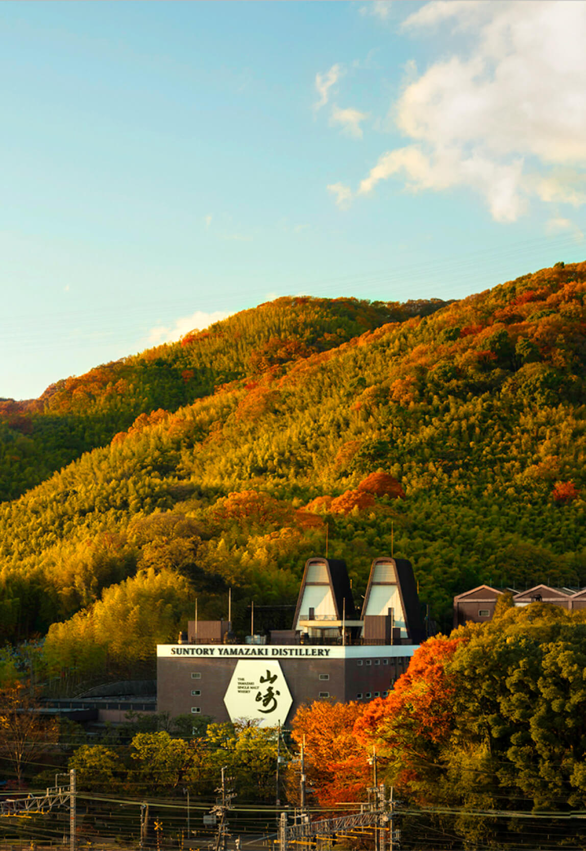 Exterior photo of Suntory’s Yamazaki Distillery and fall foliage on the hillside