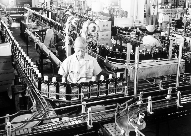 Historic black-and-white photo of the bottling line at Suntory’s Yamazaki Distillery