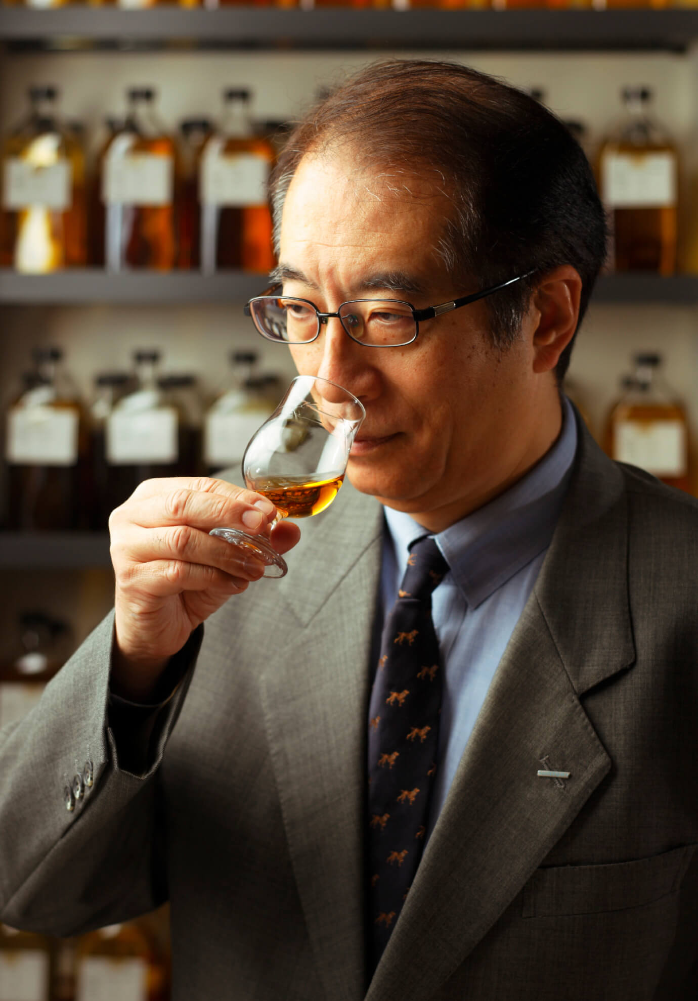 Photo of Suntory vice chairman of the board Shingo Torii sniffing a sample of Suntory product in a bottle room